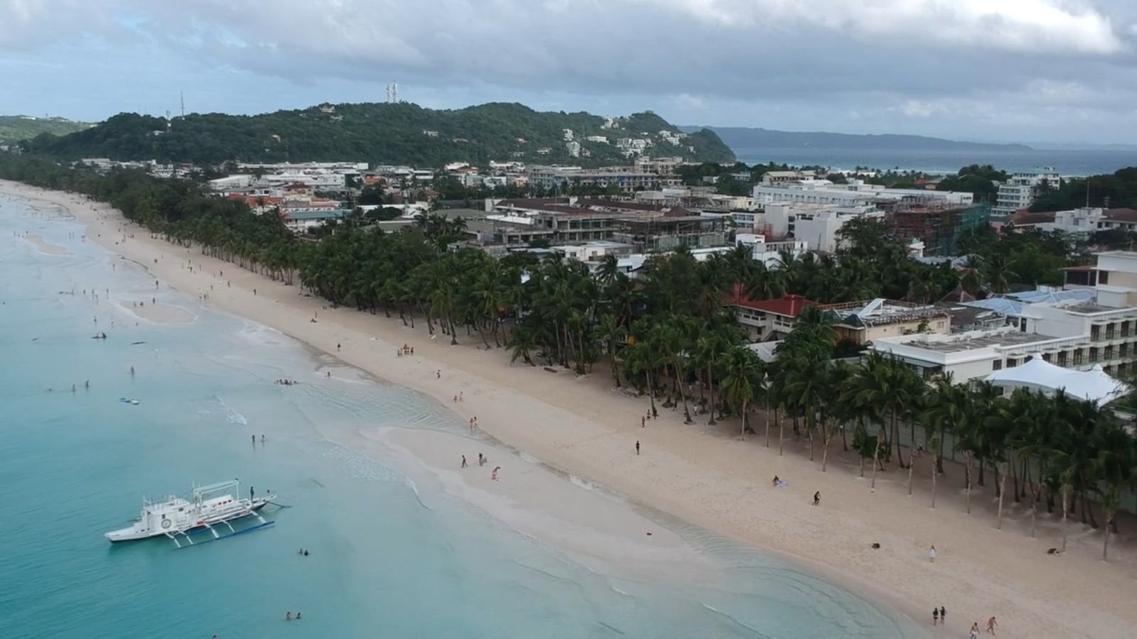 Aerial view of White Beach in Boracay, a bangka moored off the sand and palms lining the shore
