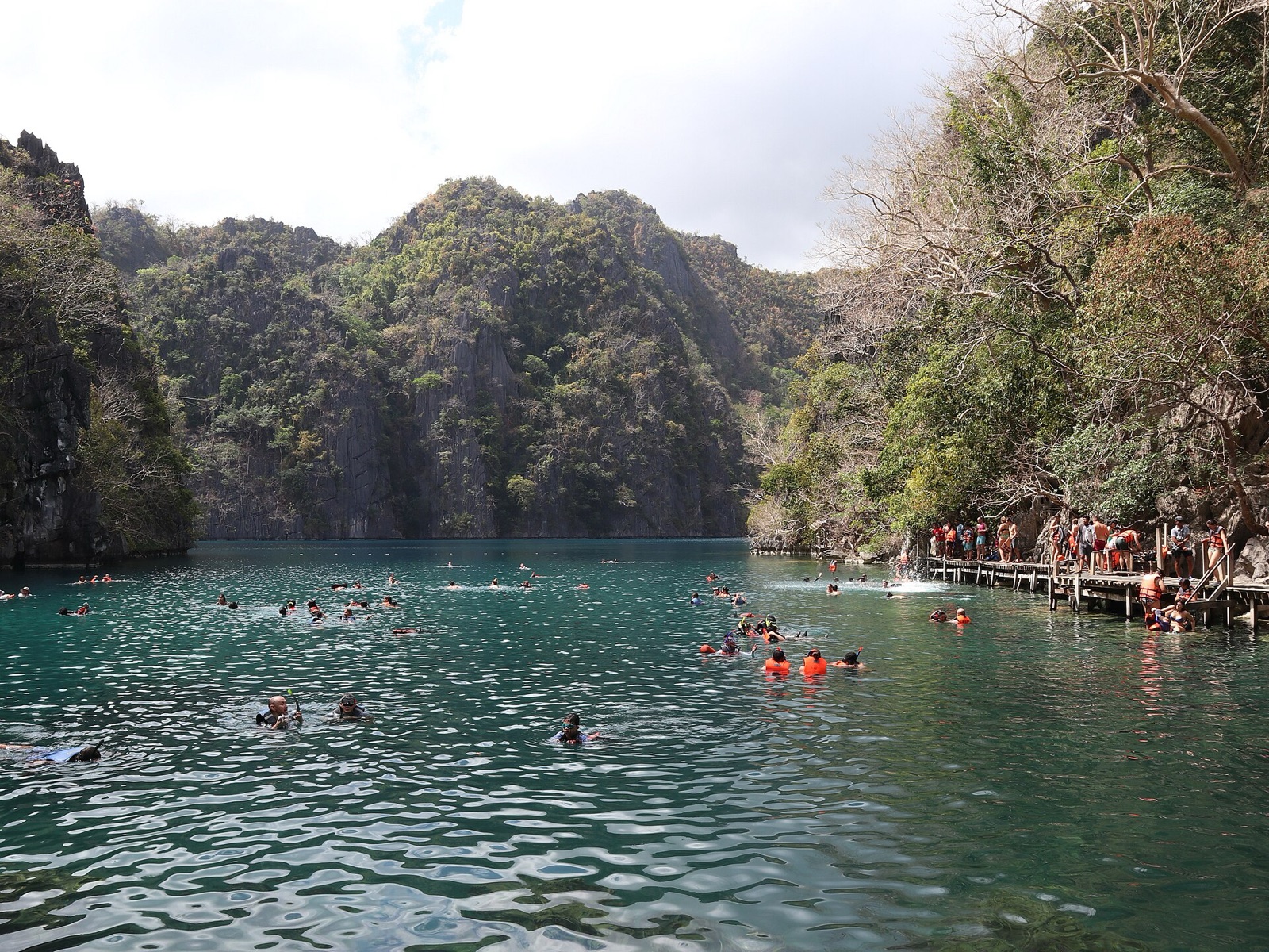 Swimmers in the emerald water of Kayangan Lake, ringed by limestone cliffs on Coron Island