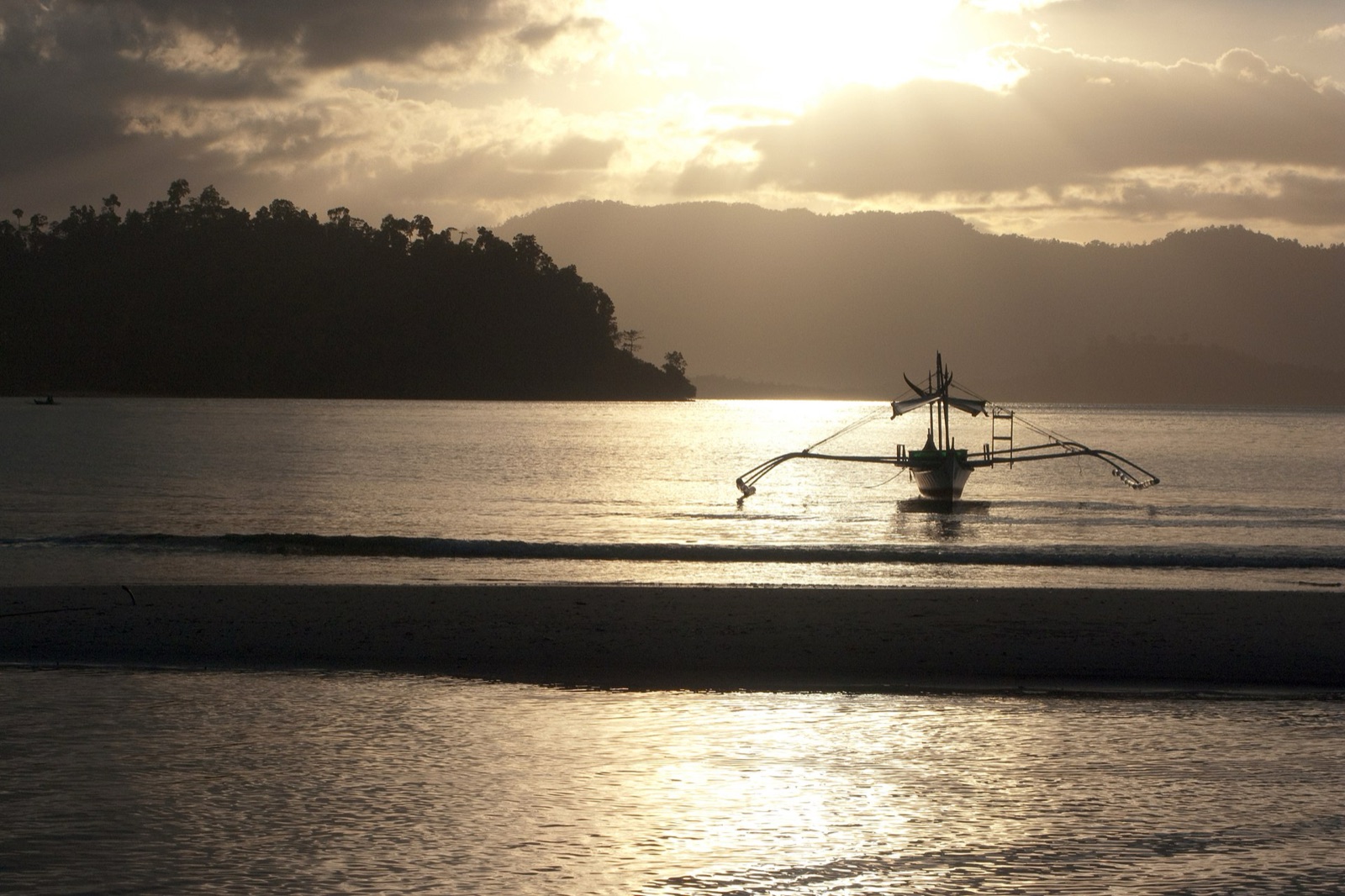Sunset over the calm bay at Port Barton, San Vicente, with outrigger boats moored offshore