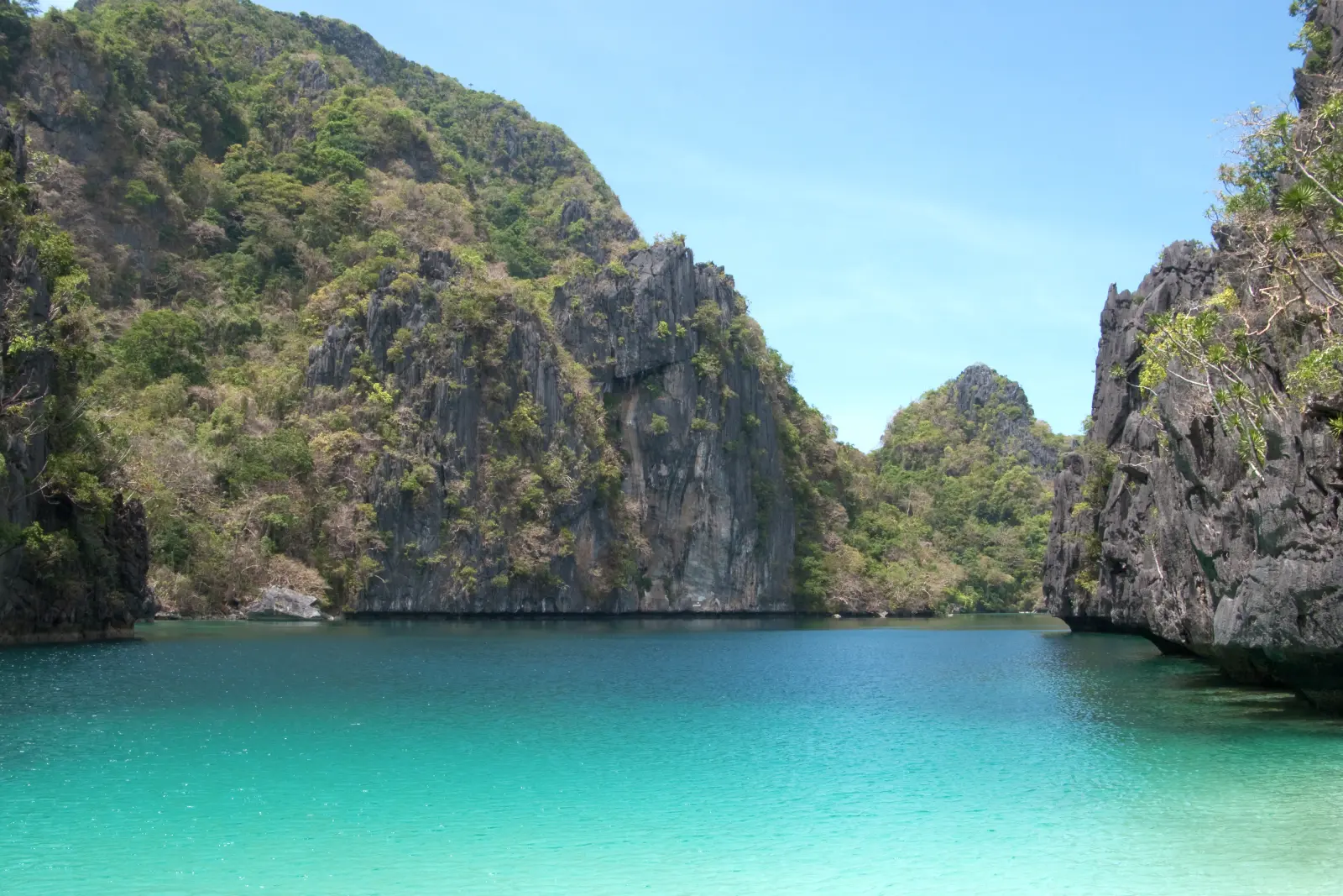 Turquoise lagoon enclosed by limestone karst cliffs in Bacuit Bay, El Nido